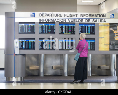 Bilingual Electronic partenza Flight Information Board e passeggero, l'Aeroporto Internazionale Liberty di Newark, Newark, New Jersey, STATI UNITI D'AMERICA Foto Stock