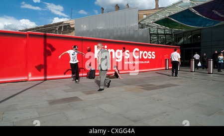 Uomo in un vestito a piedi passato ballerino break al di fuori di King Cross Stazione ferroviaria segno rosso Londra Inghilterra KATHY DEWITT Foto Stock