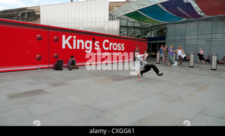 Breakdancers al di fuori di King Cross Stazione ferroviaria segno rosso Londra Inghilterra REGNO UNITO Foto Stock