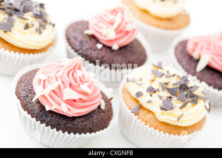 Cioccolato e vaniglia tortine smerigliati e guarnita con scaglie di cioccolato. Foto Stock