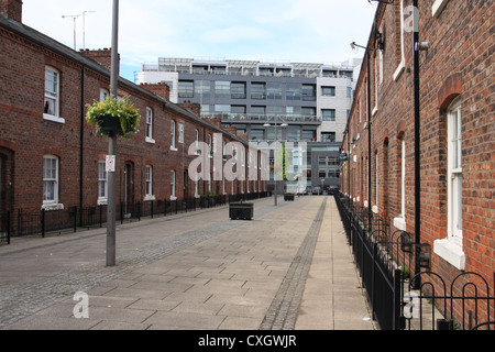 Una strada di case a schiera di Manchester con un nuovo ufficio sviluppo in background. Foto Stock