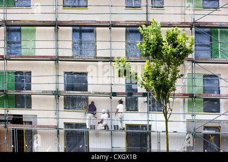 Lavoratore a un ponteggio, intonacare la parete di un nuovo edificio di appartamenti. Foto Stock