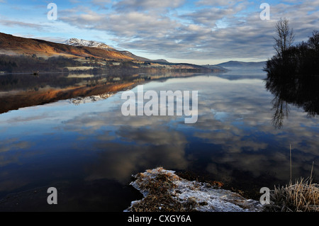 Icy sponde del Loch Tay con distante snow-capped Beinn Ghlas nella gamma Lawers, Killin, Scozia Foto Stock