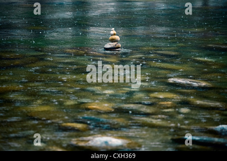 Torre in pietra in un letto del fiume sotto la pioggia Foto Stock