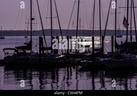 Barche a vela ormeggiata stagliano contro un cielo viola a sunrise. La luce del sole brilla sull'acqua. niantic east lyme connecticut usa Foto Stock