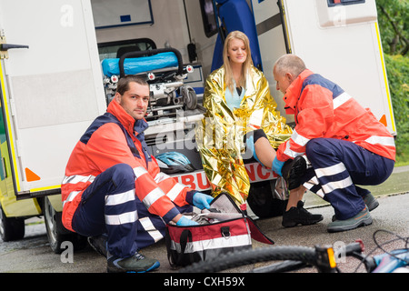 Incidente in bicicletta donna medico di emergenza controllo della gamba in ambulanza Foto Stock