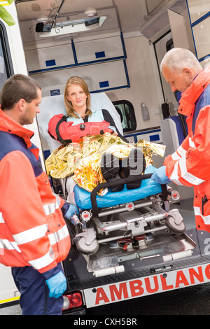 I paramedici con feriti donna sulla barella in ambulanza aiutando incidente Foto Stock