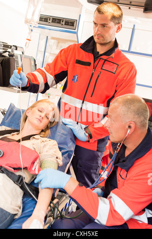 Inconscio paziente donna ambulanza emergenza personale paramedico la misura della pressione del sangue Foto Stock