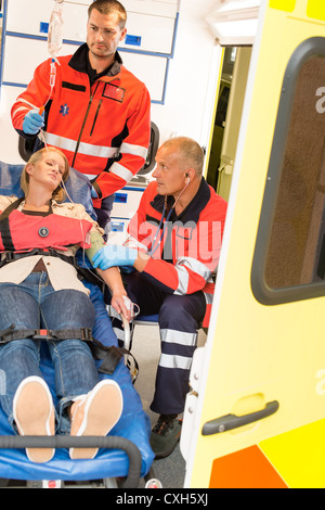 I paramedici aiutare inconscio donna ambulanza di emergenza di misurare la pressione sanguigna Foto Stock