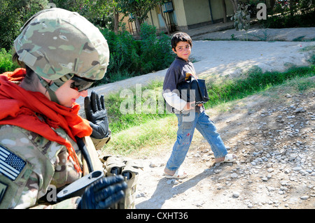 U.s. navy petty officer 1. classe theresa Richards, un ospedale corpsman assegnato al team di ricostruzione provinciale farah onde per un ragazzo afgano durante una missione nella città di Farah, provincia di Farah, Afghanistan, sett. 29. Il prt è di condurre la missione di monitorare i progressi realizzati in corrispondenza di una alimentazione terapeutica centro. prt farah è un gruppo di soldati, marinai e aviatori collaborando con vari enti pubblici e non le agenzie del governo con il compito di facilitare la governance e la stabilità nella regione da lavorare mano nella mano con i funzionari locali e il governo della Repubblica islamica dell'Afghanistan. Foto Stock