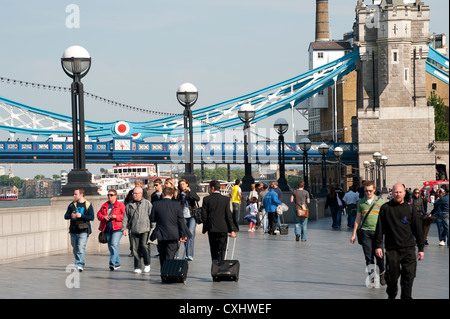 I pedoni a camminare lungo la riva sud del Tamigi, vicino al Tower Bridge di Londra, Inghilterra. Foto Stock