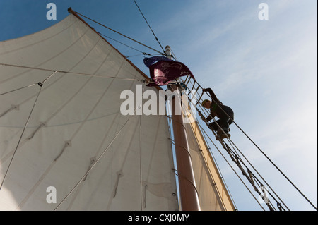 Una donna si arrampica per le manovre di una goletta per impostare una vela durante una goletta gara di Bellingham Bay, Washington. Foto Stock