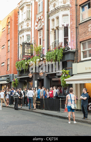 Persone in piedi al di fuori del bar Comptons a Soho, London, Regno Unito Foto Stock