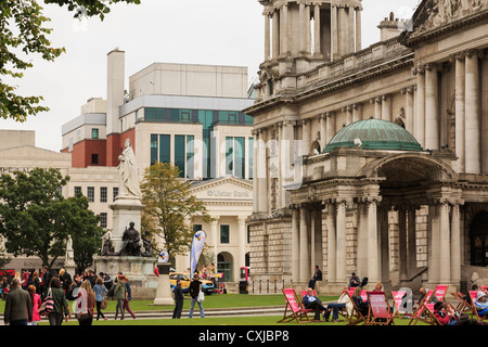 Occupato la scena con persone rilassante nei giardini del municipio in Donegall Square, Belfast, County Antrim, Irlanda del Nord, Regno Unito Foto Stock