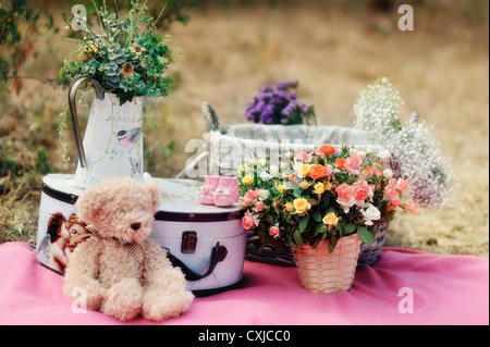 Composizione bouquet di rose in vasi valigia e toy bear Foto Stock
