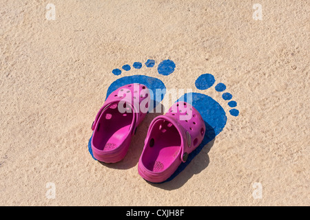 Scarpe da bambino collocato sopra dipinta di footprint a lato della piscina Foto Stock