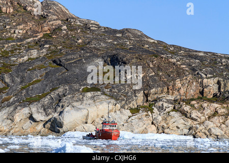 Barca da pesca nel ghiaccio soffocato Harbour di Discoteca Bay a Ilulissat a metà estate. Il ghiaccio è in porto l'anno. Foto Stock