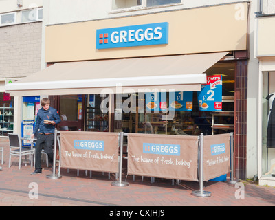 Giovane uomo proveniente da una piccola catena Greggs panificio portano il cibo da mangiare Foto Stock