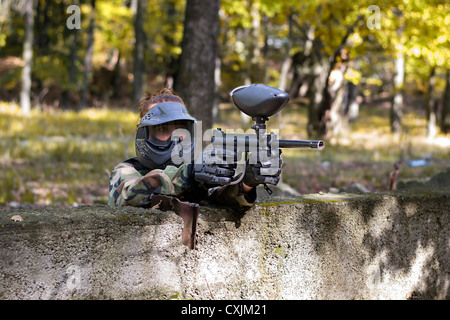 Il paintball tiro del giocatore avversario da dietro una parete durante un torneo di paintball. Foto Stock