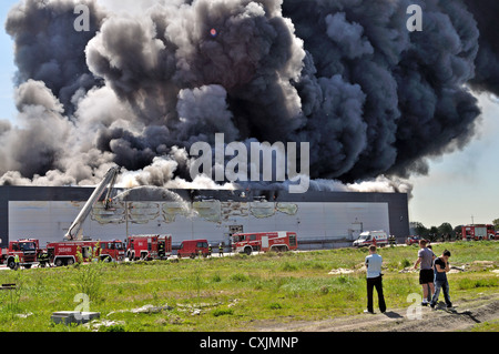 I vigili del fuoco spengono un fuoco infuriante in un magazzino. Foto Stock