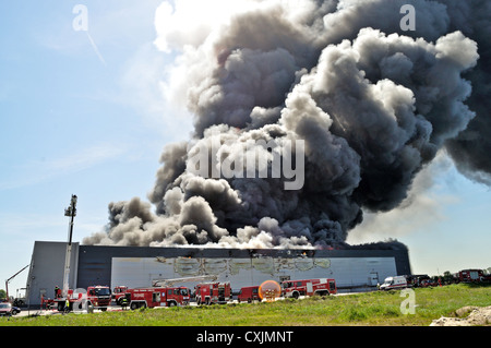 I vigili del fuoco spengono un fuoco infuriante in un magazzino. Foto Stock