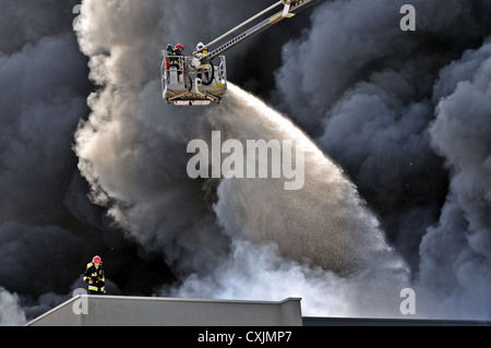 I vigili del fuoco spengono un fuoco infuriante in un magazzino. Foto Stock