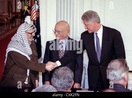 Il Presidente degli Stati Uniti Bill Clinton scuote le mani con il leader palestinese Yasser Arafat il re Hussein di Giordania si affaccia sulla prima della firma di un accordo interinale di accordo di pace noto come gli accordi di Wye Plantation in Oriente camera presso la Casa Bianca Ottobre 23, 1998 a Washington, DC. Foto Stock