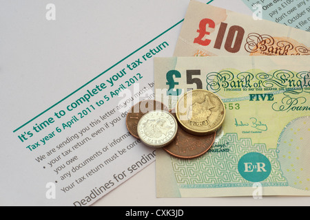 Valuta britannica (banconote e monete) giacente su una lettera dall'Inland Revenue (ufficio tributario) ricordando che è il momento di completare una Foto Stock