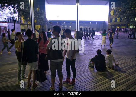 Un gruppo di giovani di me e la donna in piedi presso un centro commerciale nel quartiere di Sanlitun della centrale di Pechino, Cina. Foto Stock