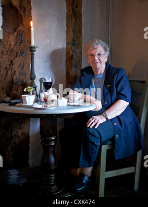 Donna di 90 anni, donna non agenaria inglese, che festeggia il suo compleanno con un bicchiere di vino rosso in un ristorante a lume di candela. Inghilterra Regno Unito Foto Stock