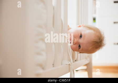 Baby girl guardando fuori dal presepe Foto Stock