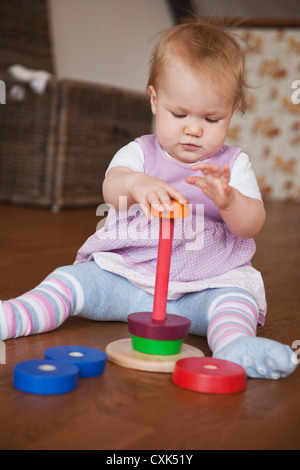 Baby ragazza seduta sul pavimento a giocare con il giocattolo Foto Stock