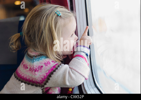 Bambina con succhietto e guardare fuori dalla finestra del treno Foto Stock