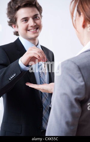 Giovane imprenditore che dà le chiavi a imprenditrice Foto Stock