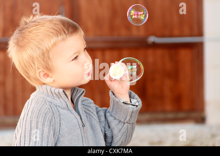 Ragazzo (3-4) che soffia bolle di sapone, Francia. Foto Stock