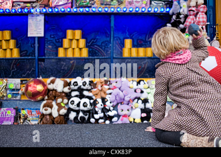 Bambina gioca gettando palla di gioco alla fiera del divertimento. Foto Stock