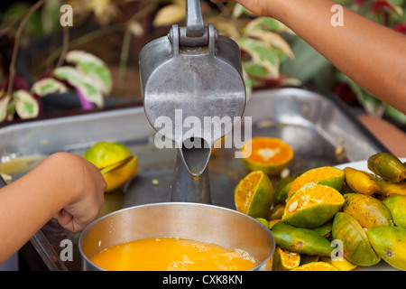 Bambina premendo il succo di arancia in Bangkok Foto Stock