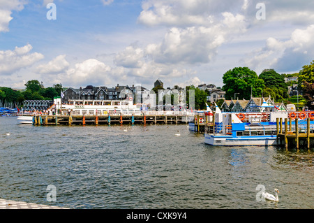 Il sole splende sui numerosi pontili di Bowness Bay con un escursione a fianco della nave a prendere i passeggeri per una crociera intorno al lago Foto Stock