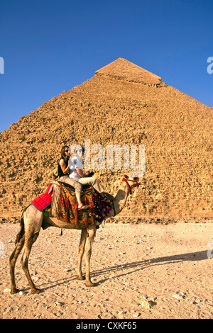 I turisti cavalcare un cammello di fronte le grandi piramidi dell'Egitto del Cairo sull'Altopiano di Giza. (MR) Foto Stock