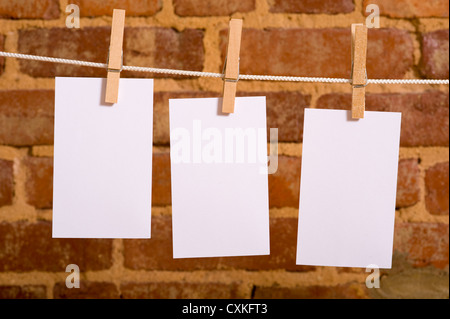 Una fila di cinque note vuote su stendibiancheria di fronte a un muro di mattoni, con spazio di copia Foto Stock