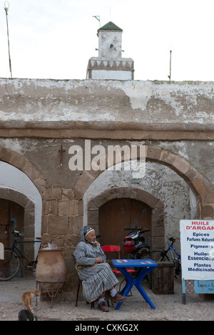 Uomo marocchino ho kaftan seduta dal negozio locale di vendita olio di Argan, Essaouira, Marocco Foto Stock