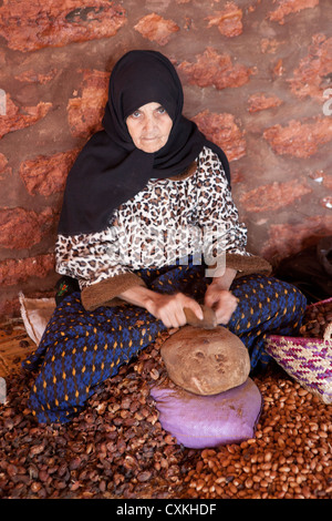 Donna marocchina di cracking dadi Argan in preparazione per la produzione di olio di Argan, Essaouira, Marocco Foto Stock