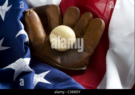 Un raggruppamento di baseball classic elementi tra cui un antico guanto o muffola e un antico baseball sulla parte superiore di una bandiera americana Foto Stock