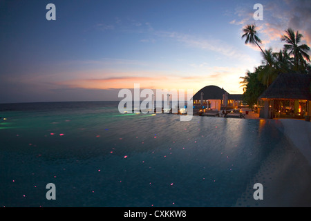 Twilight oltre la piscina infinita sull'isola resort di Huvafen da Fushi, Maldive Foto Stock