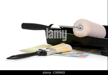 Forniture di pittura su un fondo bianco con un rolller, campioni di colore e un pennello Foto Stock