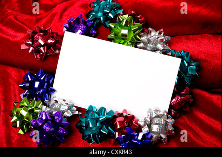 Un fustellato notecard circondato da decorazione di Natale gli archetti su uno sfondo rosso, aggiungi copia o la grafica, festa di Natale invito, Foto Stock