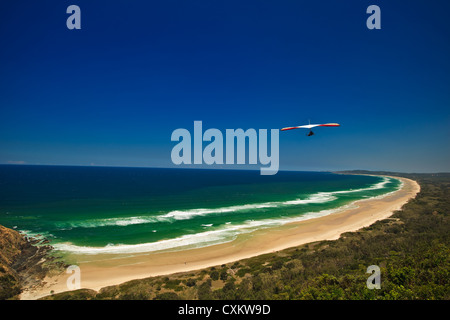 Deltaplano volare oltre incontaminata spiaggia deserta a Byron Bay Foto Stock