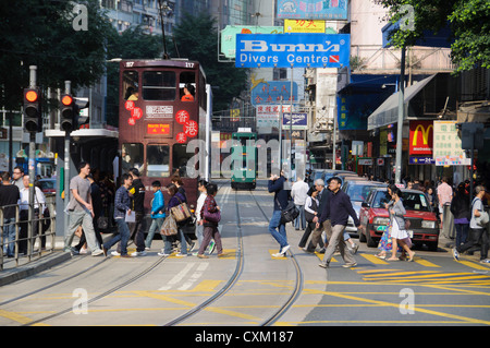 Pedoni attraversare i binari del tram sulla strada Johnston in Wan Chai district dell'Isola di Hong Kong Foto Stock