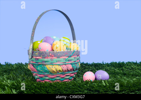 Colorate le uova di Pasqua in un cestello di erba con un cielo blu sullo sfondo