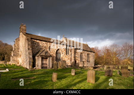 Esterno del soleggiato storica Chiesa di Tutti i Santi & sagrato lapidi in una tranquilla zona panoramica campagna sotto il cielo scuro, Weston, North Yorkshire, Inghilterra, Regno Unito Foto Stock